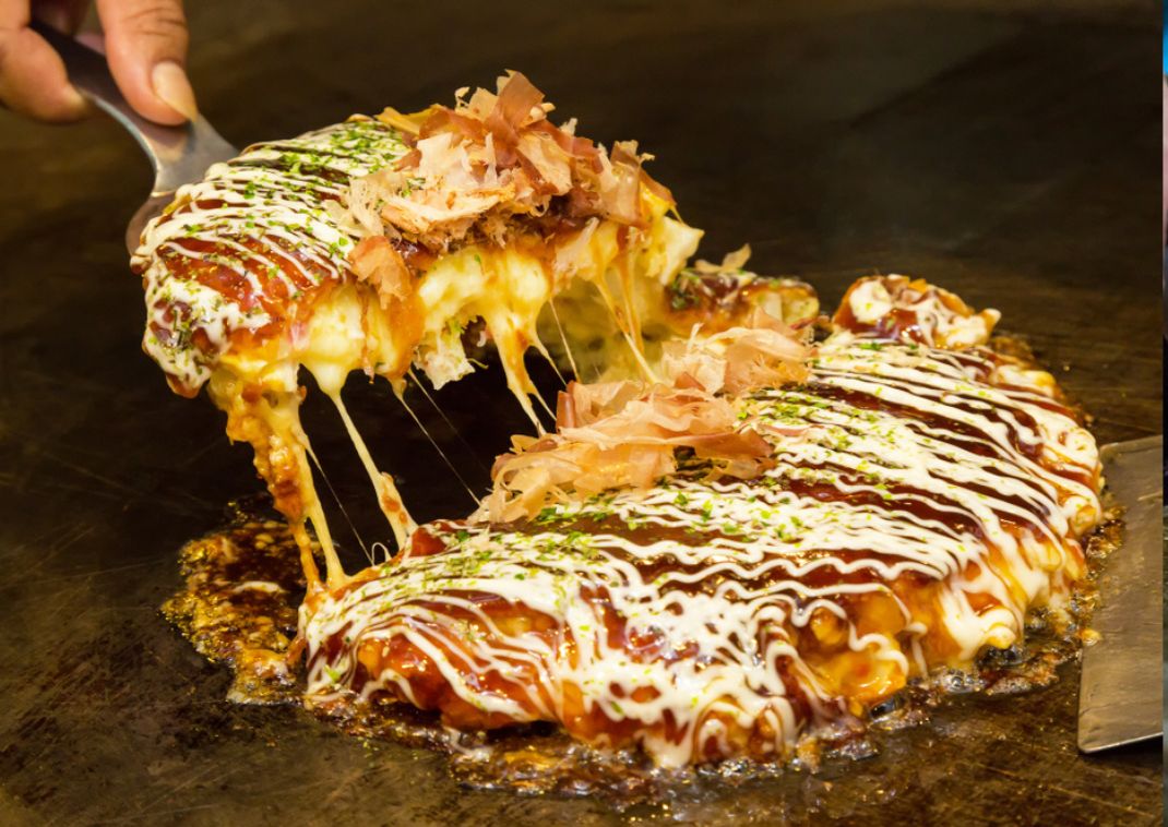 Der japanische Pfannkuchen namens Okonomiyaki wird auf einer heißen Platte gegart.