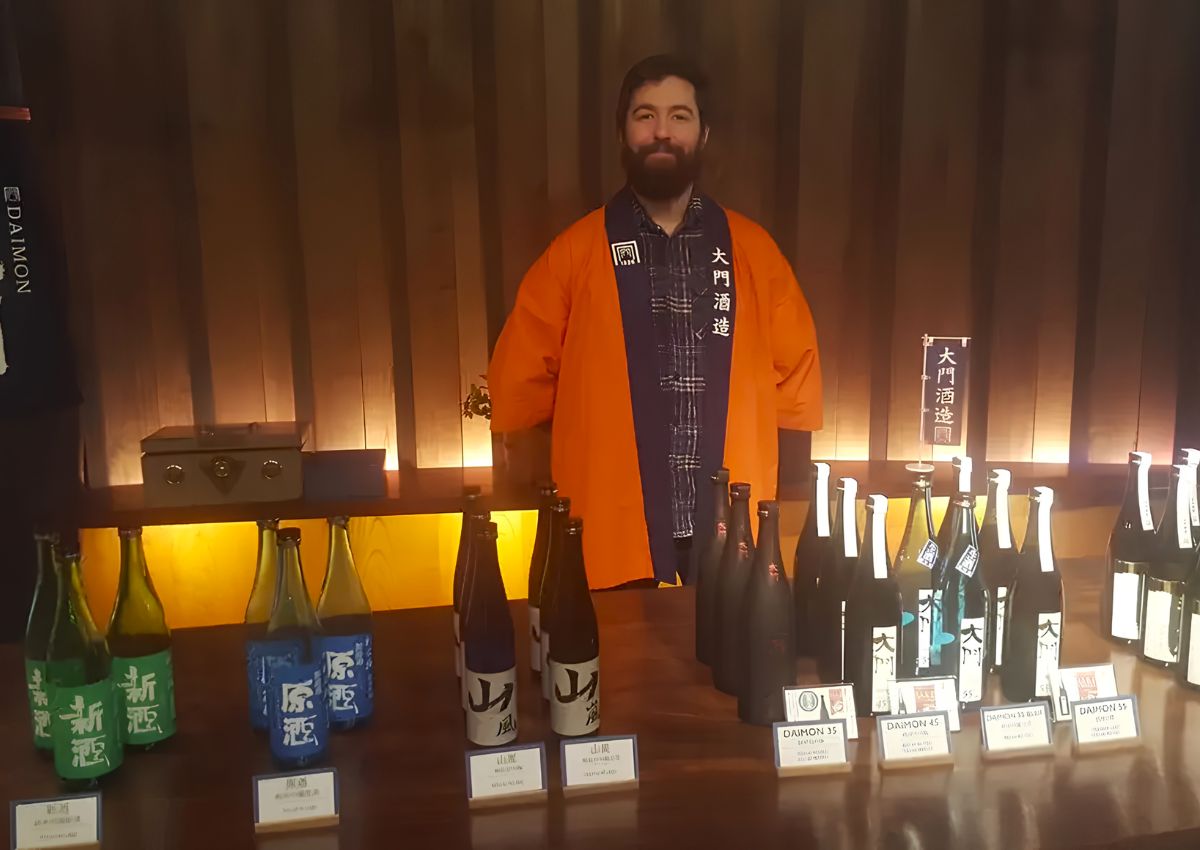 Jeremy in der Sake-Brauerei Daimon in Osaka, umgeben von Sake-Flaschen.