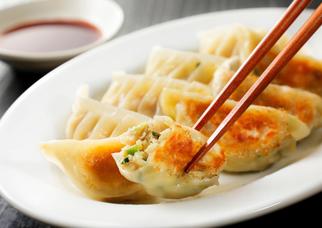  Ein köstliches gebratenes Gyoza, gehalten von einem Paar Essstäbchen