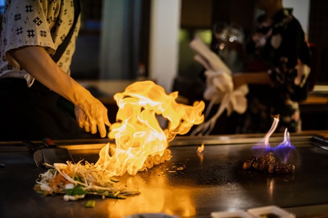 Koch bereitet Teppanyaki-Gericht mit gegrilltem Rindfleisch und Gemüse zu