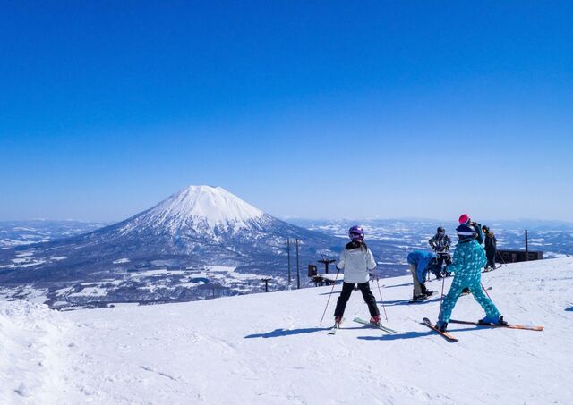 Skifahrer schauen an einem klaren Tag auf den verschneiten Vulkan