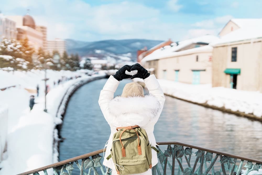 Touristen beim Sightseeing entlang des verschneiten Otaru-Kanals in Hokkaido, Japan, und genießen die Wintersaison