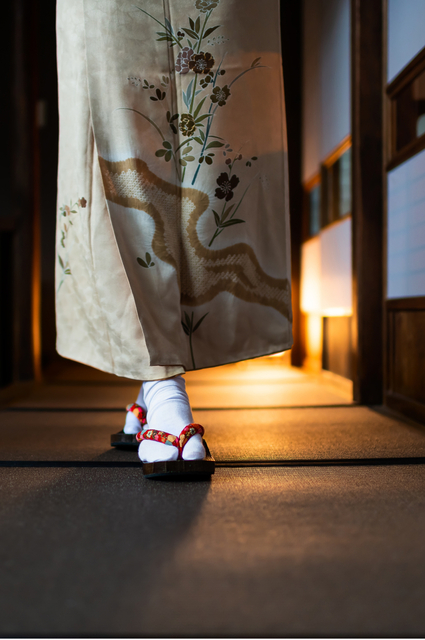 Frau im Kimono geht durch einen traditionellen Ryokan mit Tatami-Matten und Shoji-Türen