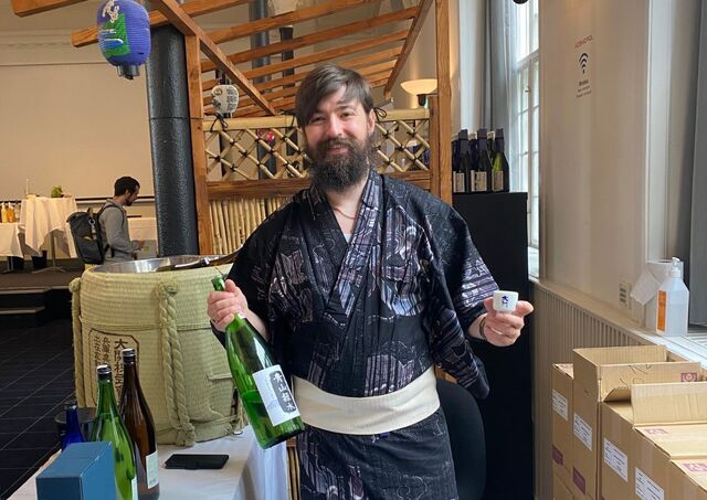 Jeremy hält eine Sake-Flasche und –Tasse in den Händen.